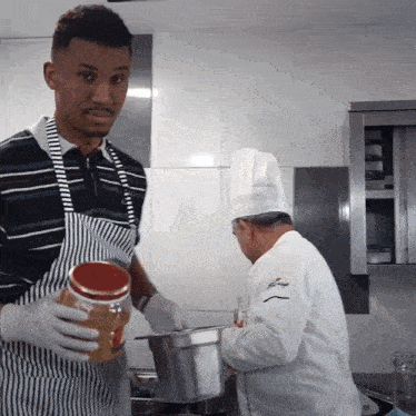a man holding a jar of peanut butter stands next to another man in a chef 's hat