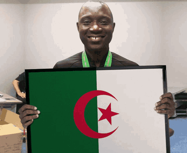 a man holds a framed picture of the algerian flag