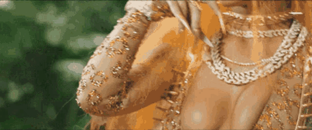 a close up of a woman wearing a gold dress and chains