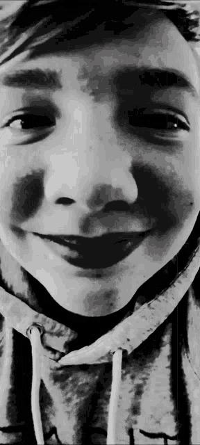 a black and white photo of a young boy wearing a grey hoodie