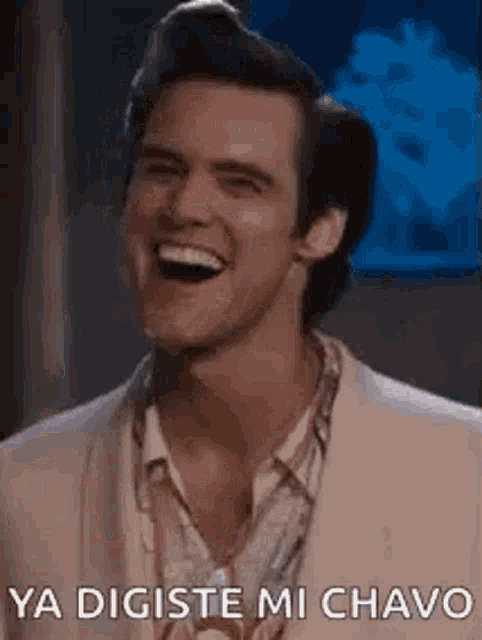 a man in a suit is laughing with the words `` ya digite mi chavo '' written next to him .