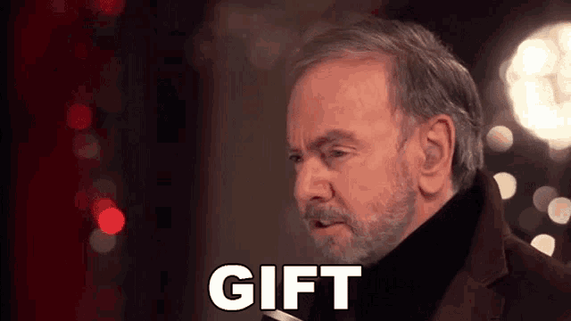 a man with a beard is talking into a microphone with the word gift written next to him .