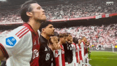 a group of soccer players standing in a line with the number 23 on the scoreboard behind them