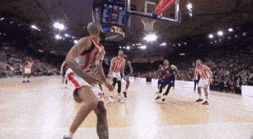 a basketball game is being played in front of a crowd and a scoreboard that says ' barcelona ' at the top