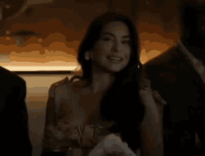 a woman in a dress is smiling in a dark room .