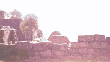 a red car is parked in front of a stone wall with ruins in the background