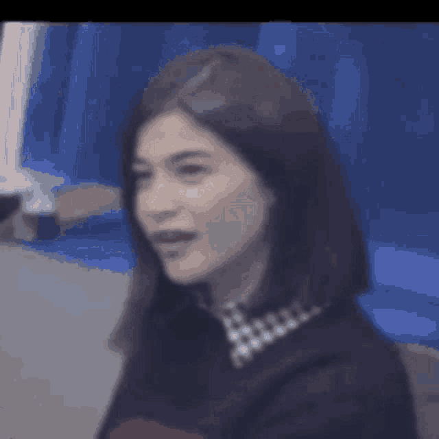 a close up of a woman 's face with a blue background and a blurred background .