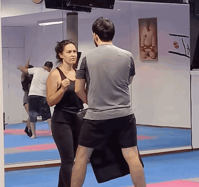 a man and a woman are boxing in front of a mirror in a gym