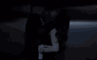 a man and woman are kissing in an elevator in a dark room .