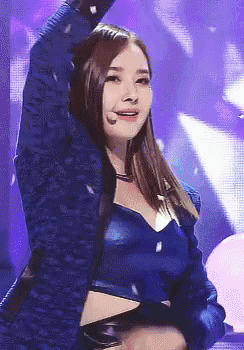 a woman in a blue crop top is dancing on stage