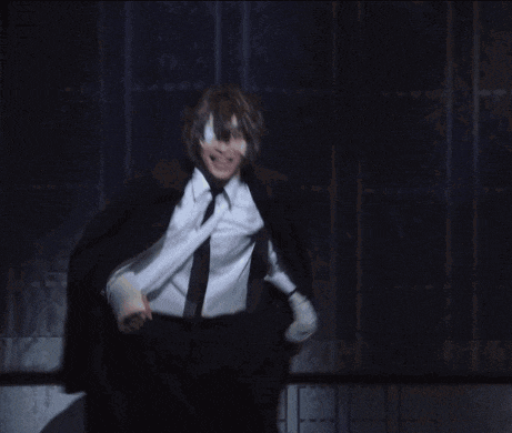 a man in a black suit and tie is dancing on a stage