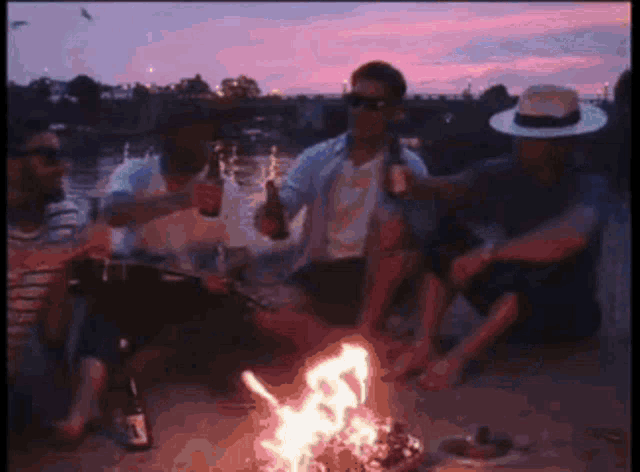 a group of men are sitting around a campfire
