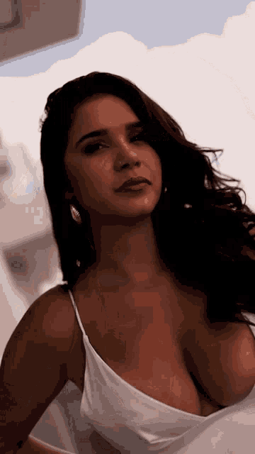 a woman in a white tank top has a very plunging neckline