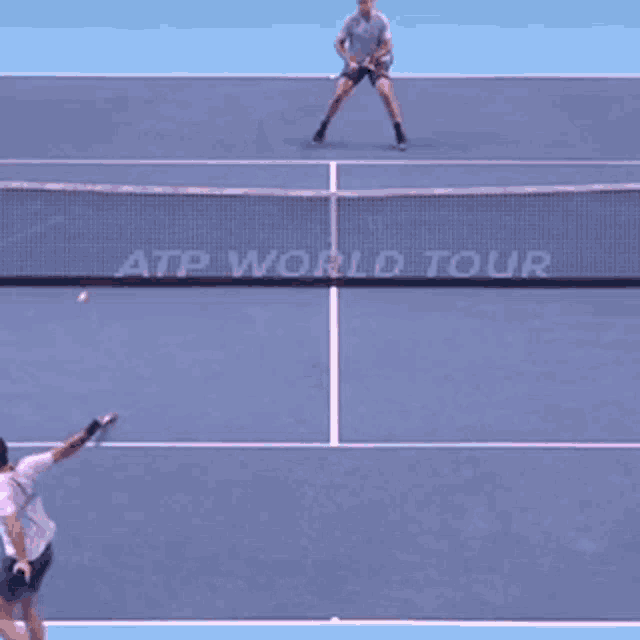 two men are playing tennis in front of a net that says atp world tour on it