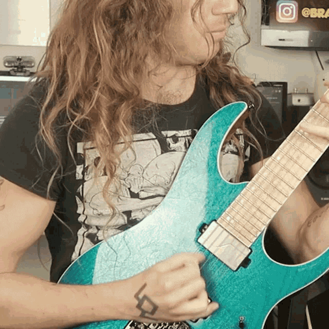 a man with long hair is playing a blue guitar in front of an instagram logo