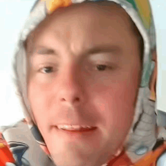 a close up of a man wearing a hoodie and a scarf around his head .