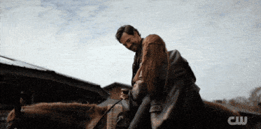 a man and a woman are standing next to a horse with the letters cw on the bottom