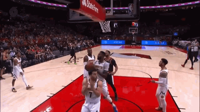 a basketball game is being played in a stadium with a state farm banner hanging from the hoop