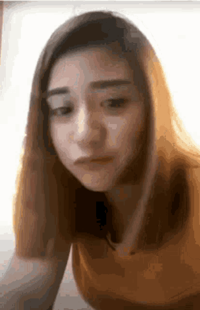 a woman in a yellow shirt is making a funny face and looking at the camera .