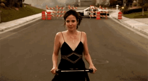 a woman in a black dress is walking down a street