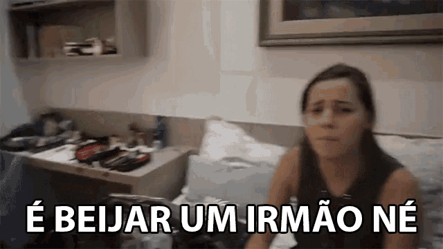 a woman is sitting on a bed with the words " e beijar um irmao ne " written above her