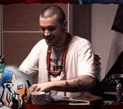 a man wearing a white shirt and a necklace that says ' a ' on it