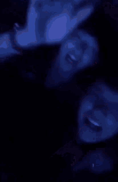 a group of people are dancing in a dark room and one of them is wearing a blue headband