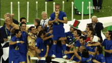 a group of soccer players celebrate with a trophy in front of a fifa tv sign