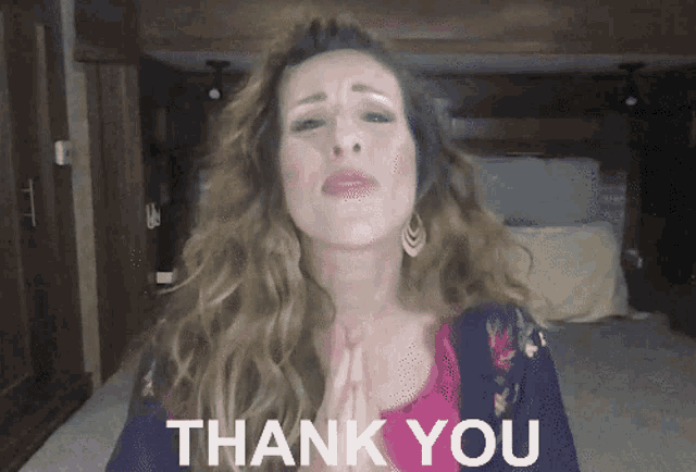 a woman is saying thank you with her hands folded in front of her face
