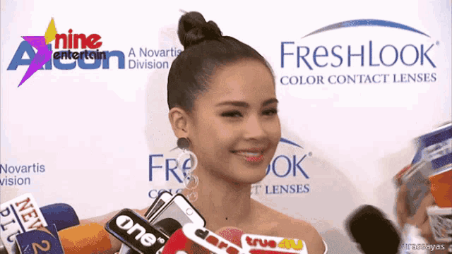 a woman stands in front of a freshlook color contact lens advertisement