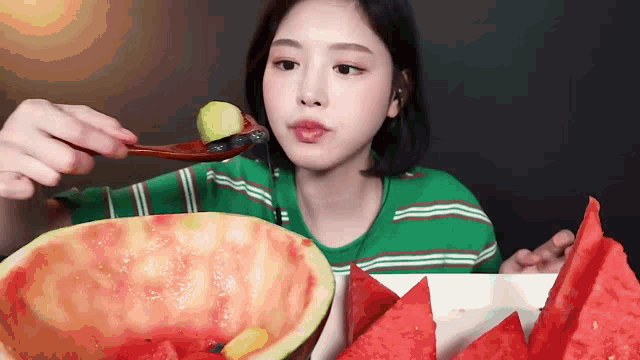 a woman is eating a watermelon with a spoon