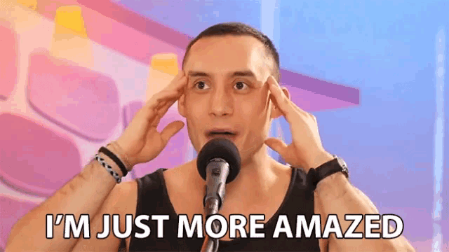 a man in front of a microphone with his hands on his head and the words i 'm just more amazed