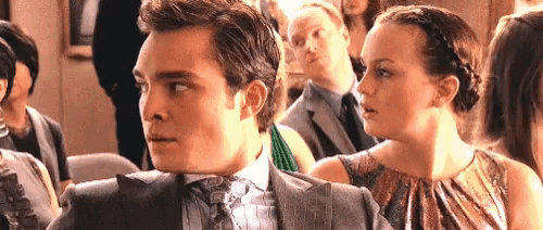 a man and a woman are sitting in a crowd of people at a party .