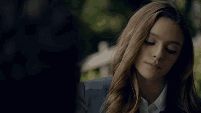 a woman in a blue jacket and white shirt looks down