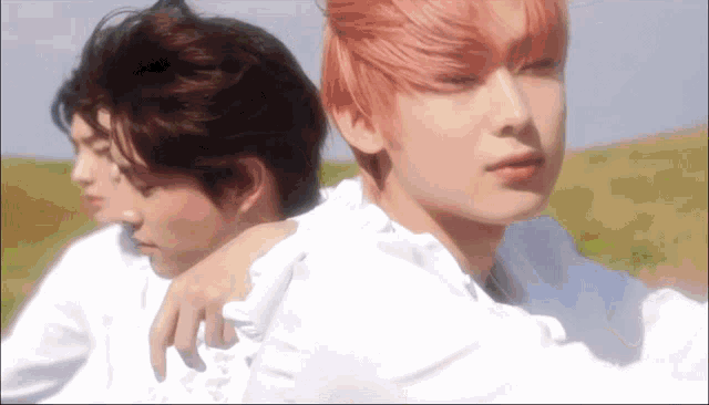 a man with pink hair is hugging another man