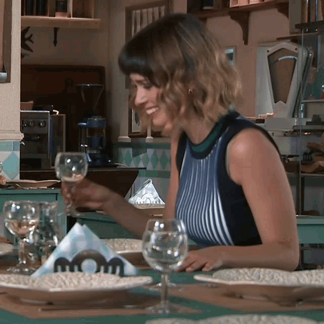 a woman sitting at a table with plates and glasses and a napkin that has the letter m on it