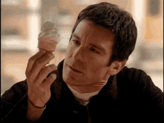 a man is holding an ice cream cone in his hand and looking at it