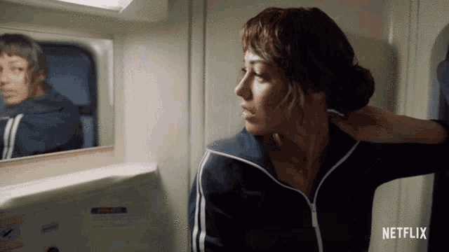 a woman is looking at her reflection in a mirror with netflix written on the bottom