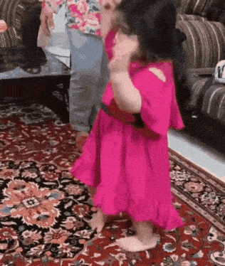 a little girl is dancing on a rug in a living room .