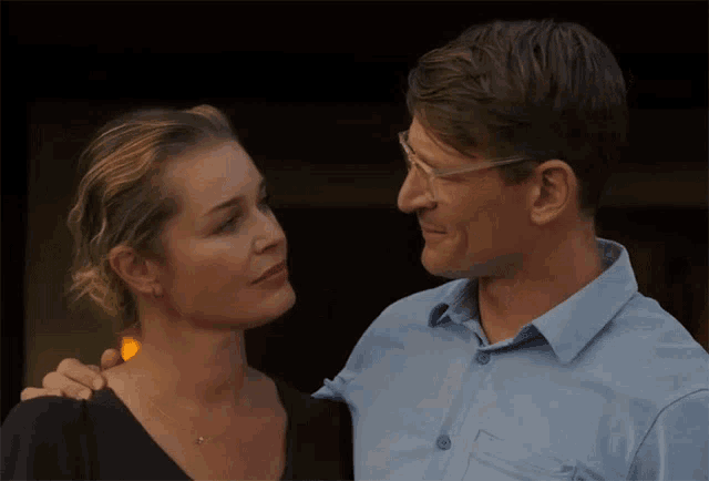 a man and a woman are looking at each other and the woman is wearing glasses