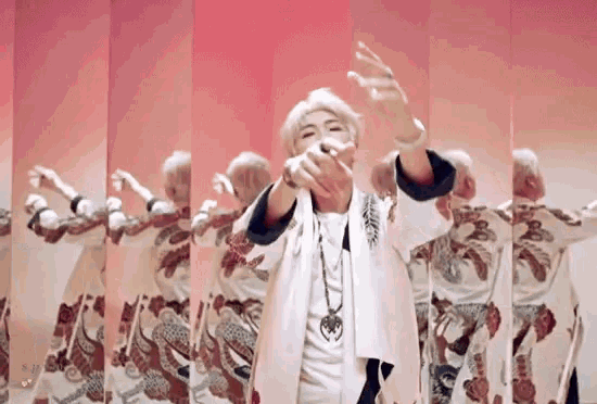 a man in a white shirt is dancing in front of a pink wall