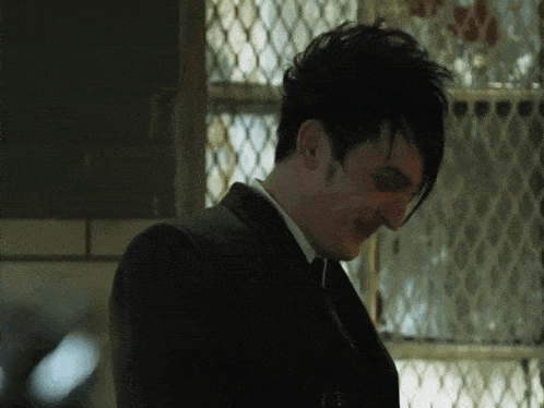 a man in a suit and tie is smiling in front of a wire fence