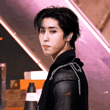 a close up of a person wearing a black shirt with a chain around his shoulder