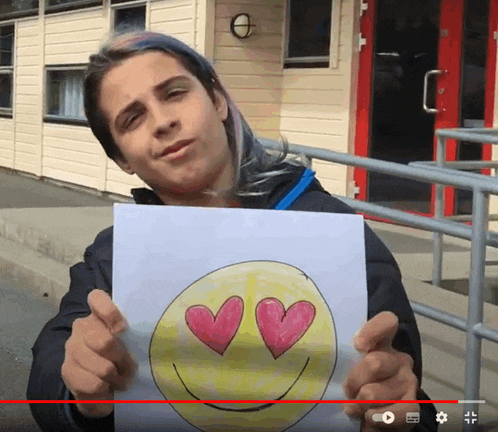 a person is holding a drawing of a smiley face with hearts in its eyes