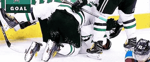 a hockey player is laying on the ice with a goal sign above him