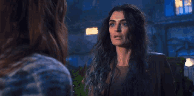 two women are standing next to each other in a dark room at night .