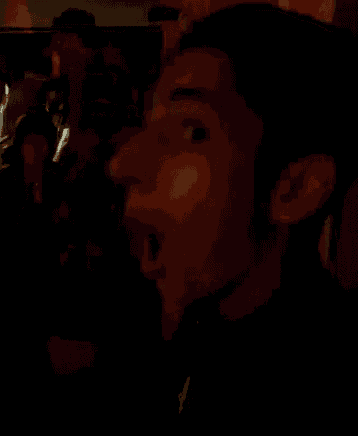 a man 's face is shown in a dark room with a blurred background