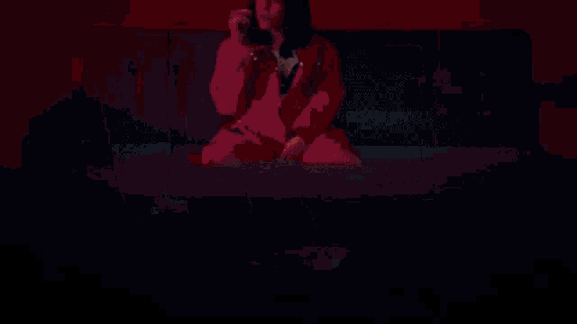 a woman is lighting a cigarette with a lighter while standing in front of a pink background .