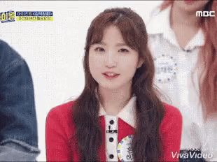 a girl in a red sweater is smiling and wearing a name tag that says mbc