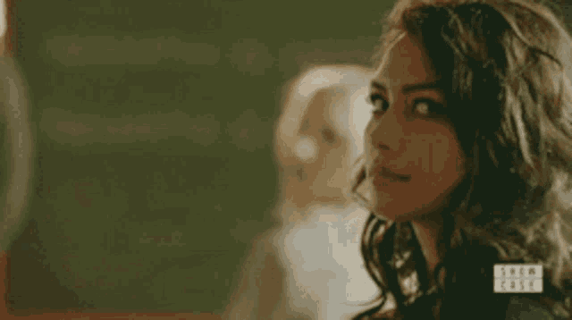 a close up of a woman 's face in front of a chalkboard with a ghost in the background .